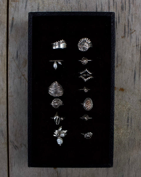 Set of silver rings displayed on a black card against a wooden background
