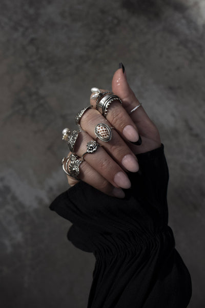 Hand wearing multiple rings on a dark background